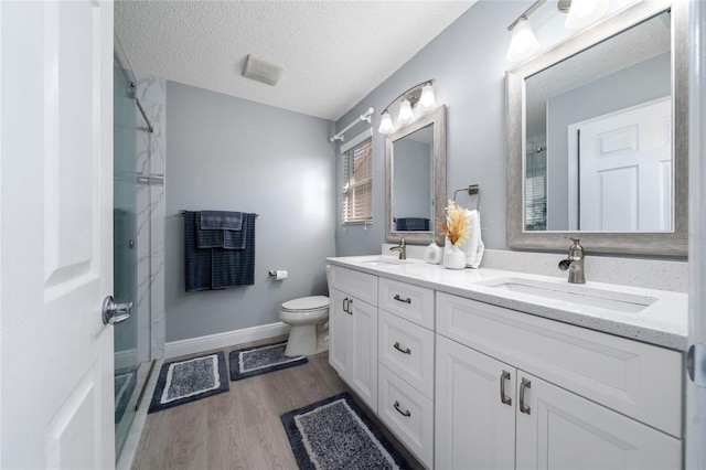 9430 SE 176th Saffold St, The Villages, FL 32162 - bathroom with double vanity, wood finished floors, toilet, a textured ceiling, and a shower