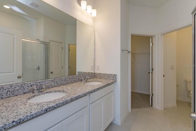 520 Silver Palm Dr, Haines City, FL 33844 - bathroom with double vanity, a shower stall, toilet, a walk in closet, and tile patterned floors