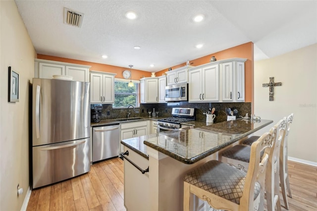 8039 SE 174th Belhaven Loop, The Villages, FL 32162 - kitchen with stainless steel appliances, a sink, a peninsula, dark stone counters, and baseboards