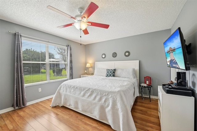 8039 SE 174th Belhaven Loop, The Villages, FL 32162 - bedroom with a textured ceiling, wood finished floors, baseboards, and a ceiling fan