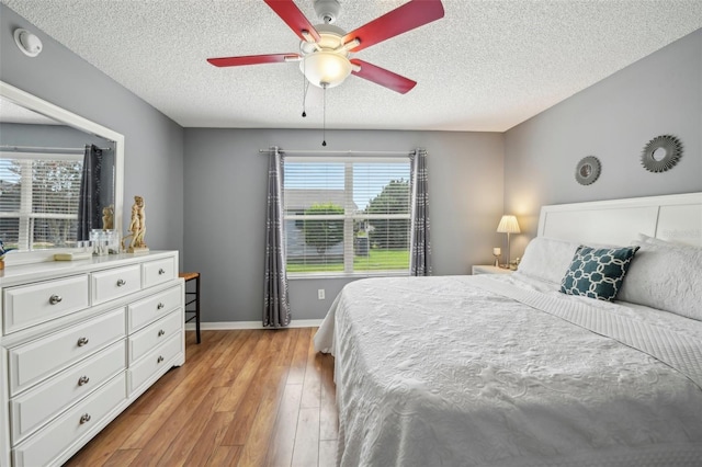 8039 SE 174th Belhaven Loop, The Villages, FL 32162 - bedroom featuring light wood-style floors, a textured ceiling, baseboards, and a ceiling fan