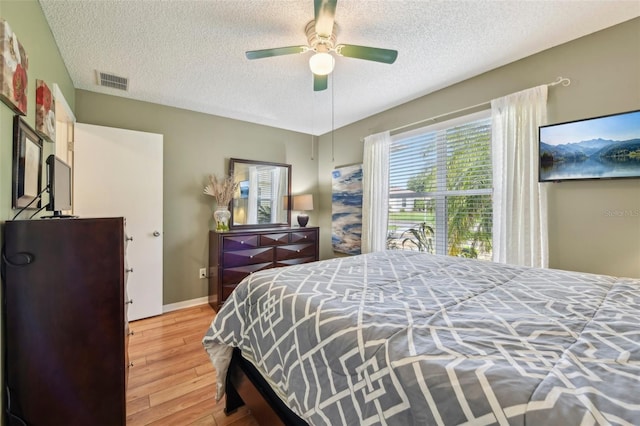 8039 SE 174th Belhaven Loop, The Villages, FL 32162 - bedroom with a textured ceiling, wood finished floors, a ceiling fan, and baseboards