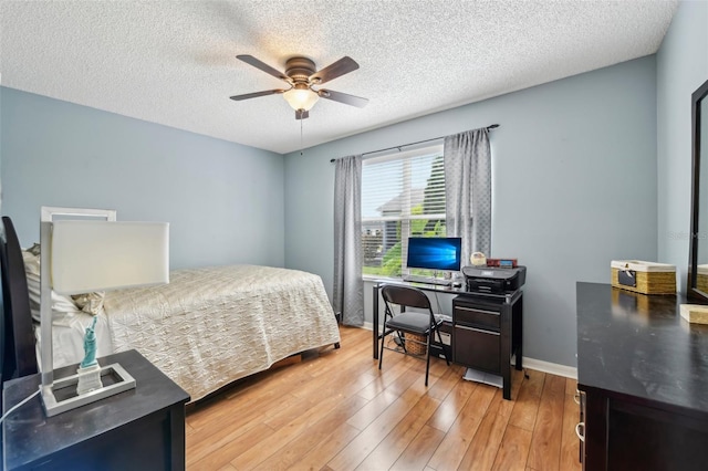 8039 SE 174th Belhaven Loop, The Villages, FL 32162 - bedroom featuring a textured ceiling, light wood-type flooring, a desk, ceiling fan, and baseboards