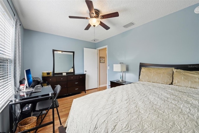 8039 SE 174th Belhaven Loop, The Villages, FL 32162 - bedroom featuring light wood-style flooring, a textured ceiling, a desk, and ceiling fan
