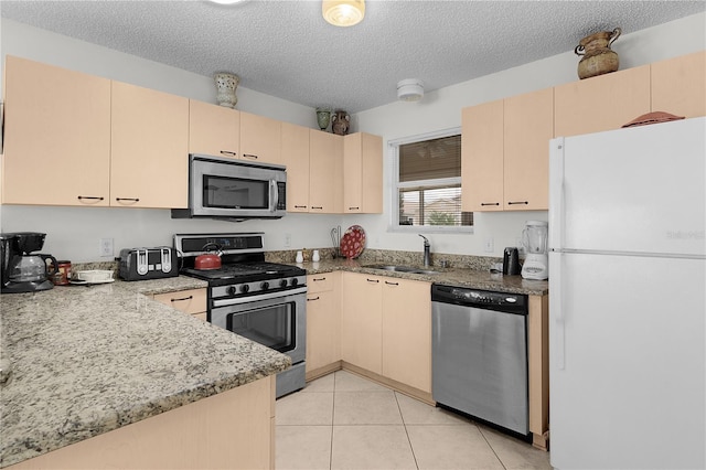 9321 SE 172nd Augusta Ln, The Villages, FL 32162 - kitchen with stainless steel appliances, a sink, a textured ceiling, light stone counters, and light tile patterned floors