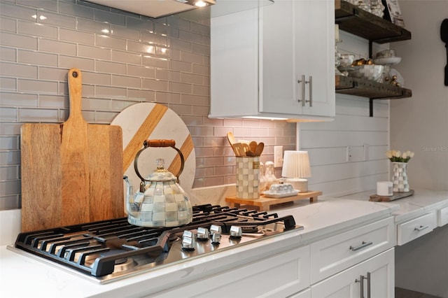 9512 Mid Summer Ln, Leesburg, FL 34788 - kitchen with stainless steel gas cooktop, decorative backsplash, open shelves, white cabinets, and light stone counters