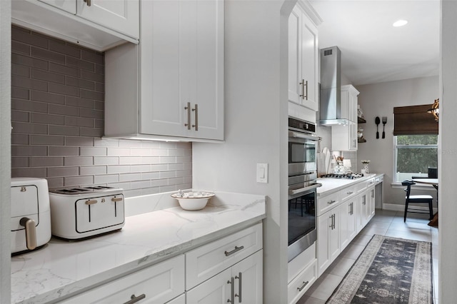 9512 Mid Summer Ln, Leesburg, FL 34788 - kitchen with tasteful backsplash, white cabinets, light tile patterned flooring, stainless steel appliances, and wall chimney range hood