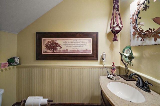707 S Dixie Dr, Howey In The Hills, FL 34737 - half bathroom featuring wainscoting, vanity, lofted ceiling, and toilet