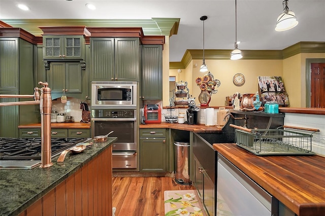 707 S Dixie Dr, Howey In The Hills, FL 34737 - kitchen featuring butcher block counters, stainless steel appliances, a warming drawer, crown molding, and light wood-type flooring