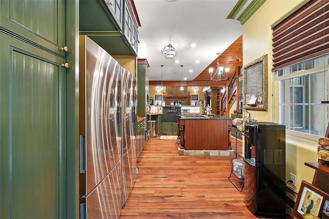 707 S Dixie Dr, Howey In The Hills, FL 34737 - kitchen featuring dark countertops, light wood-style floors, a center island with sink, a chandelier, and decorative light fixtures