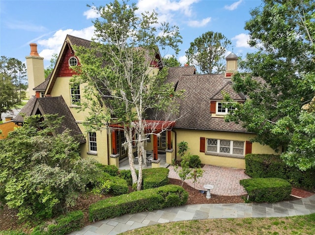 707 S Dixie Dr, Howey In The Hills, FL 34737 - english style home featuring stucco siding, a patio area, a chimney, and a shingled roof