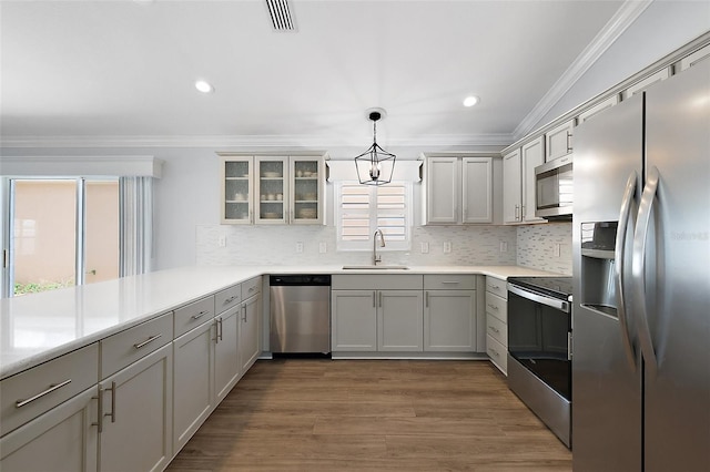 997 Oscar Ln, The Villages, FL 32162 - kitchen featuring appliances with stainless steel finishes, a sink, crown molding, backsplash, and wood finished floors