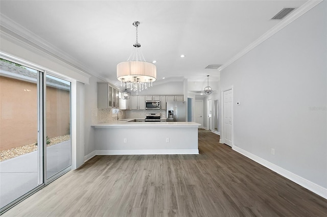 997 Oscar Ln, The Villages, FL 32162 - kitchen featuring stainless steel appliances, a chandelier, wood finished floors, light countertops, and ornamental molding