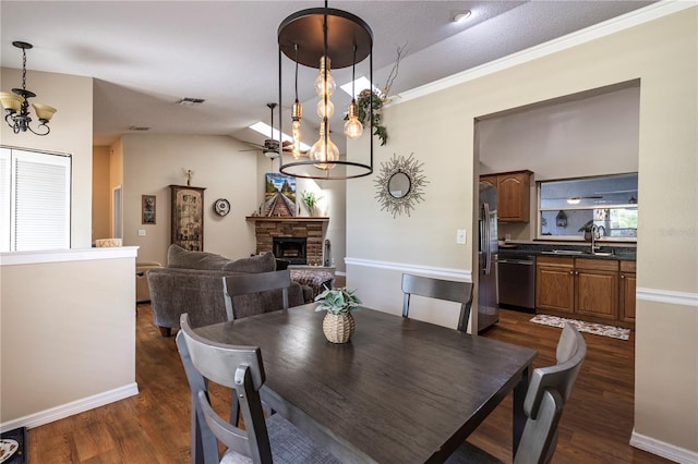 5521 Oak St, Mount Dora, FL 32757 - dining space with a chandelier, dark wood finished floors, a stone fireplace, baseboards, and a ceiling fan