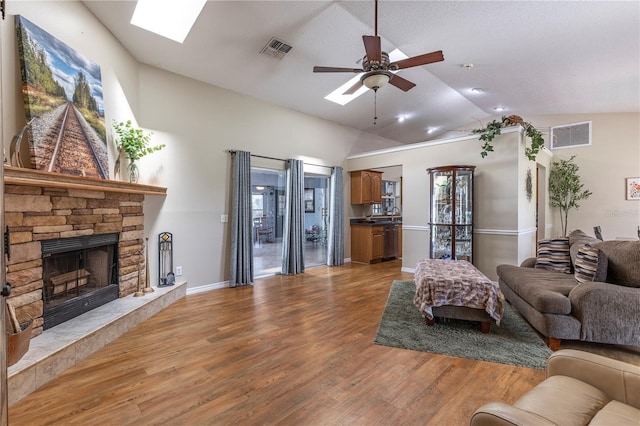 5521 Oak St, Mount Dora, FL 32757 - living area with a skylight, ceiling fan, vaulted ceiling, light wood-style floors, and a fireplace