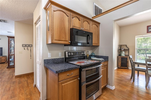 5521 Oak St, Mount Dora, FL 32757 - kitchen featuring range with two ovens, black microwave, light wood finished floors, a textured ceiling, and baseboards