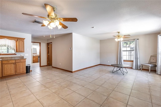 5521 Oak St, Mount Dora, FL 32757 - unfurnished living room with a ceiling fan, a textured ceiling, light tile patterned floors, and baseboards