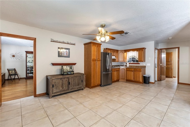 5521 Oak St, Mount Dora, FL 32757 - kitchen featuring freestanding refrigerator, ceiling fan, brown cabinets, light tile patterned flooring, and a sink