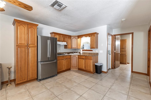 5521 Oak St, Mount Dora, FL 32757 - kitchen featuring freestanding refrigerator, under cabinet range hood, baseboards, brown cabinets, and white stovetop