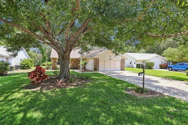 1011 Dundee Cir, Leesburg, FL 34788 - view of front of home featuring driveway, stone siding, an attached garage, and a front lawn