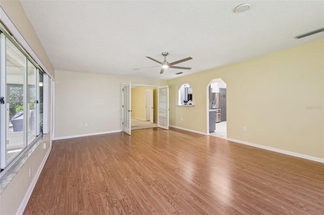 1011 Dundee Cir, Leesburg, FL 34788 - empty room with wood finished floors, ceiling fan, baseboards, and arched walkways