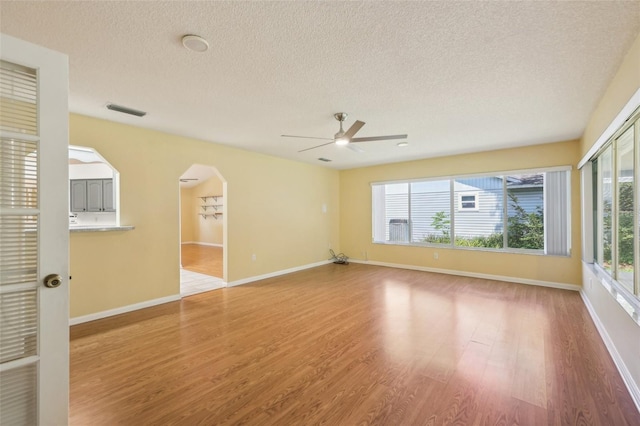 1011 Dundee Cir, Leesburg, FL 34788 - unfurnished room featuring a ceiling fan, wood finished floors, a textured ceiling, healthy amount of natural light, and arched walkways