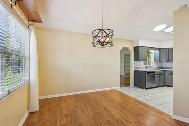 1011 Dundee Cir, Leesburg, FL 34788 - kitchen featuring gray cabinetry, arched walkways, stainless steel dishwasher, light wood finished floors, and baseboards
