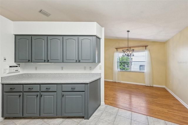 1011 Dundee Cir, Leesburg, FL 34788 - kitchen with gray cabinets, light tile patterned floors, light countertops, a chandelier, and lofted ceiling