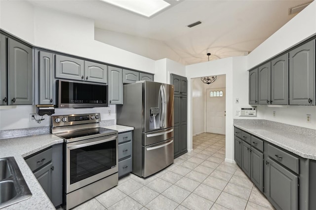 1011 Dundee Cir, Leesburg, FL 34788 - kitchen with appliances with stainless steel finishes, gray cabinetry, lofted ceiling, light tile patterned floors, and light countertops