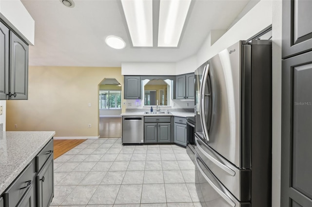 1011 Dundee Cir, Leesburg, FL 34788 - kitchen with appliances with stainless steel finishes, arched walkways, gray cabinetry, a sink, and light tile patterned flooring