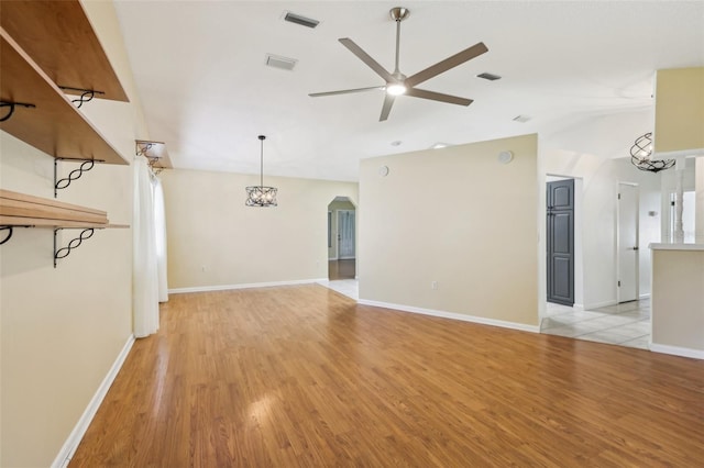 1011 Dundee Cir, Leesburg, FL 34788 - unfurnished living room with ceiling fan, light wood finished floors, vaulted ceiling, arched walkways, and baseboards