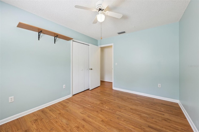 1011 Dundee Cir, Leesburg, FL 34788 - unfurnished bedroom with wood finished floors, a textured ceiling, baseboards, and a closet