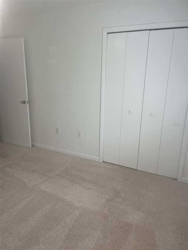 1011 Dundee Cir, Leesburg, FL 34788 - unfurnished bedroom with light colored carpet, baseboards, and a closet