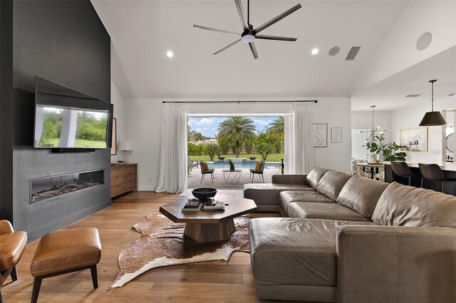 35449 Pinegate Trl, Eustis, FL 32736 - living area with high vaulted ceiling, a ceiling fan, light wood-type flooring, a glass covered fireplace, and recessed lighting
