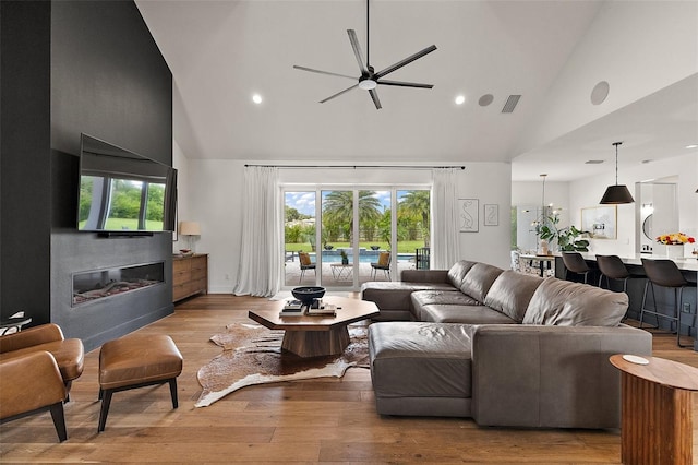 35449 Pinegate Trl, Eustis, FL 32736 - living room with high vaulted ceiling, ceiling fan, a glass covered fireplace, recessed lighting, and wood finished floors