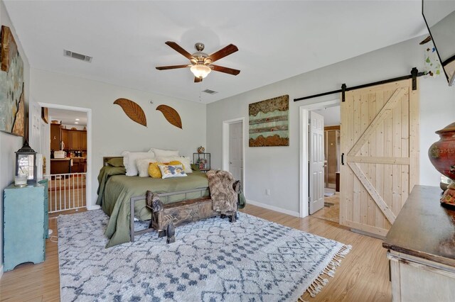 21320 Paradise Way, Eustis, FL 32736 - bedroom featuring a barn door, light wood-style flooring, baseboards, and ceiling fan