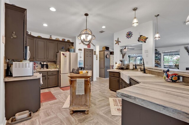 21320 Paradise Way, Eustis, FL 32736 - kitchen with freestanding refrigerator, a sink, stainless steel microwave, light countertops, and a center island