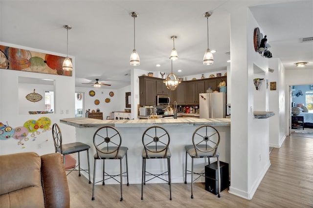 21320 Paradise Way, Eustis, FL 32736 - kitchen with freestanding refrigerator, stainless steel microwave, a breakfast bar, light wood-type flooring, and backsplash
