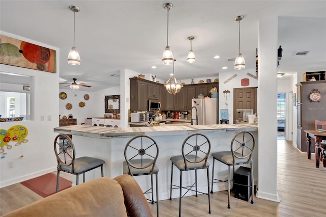 21320 Paradise Way, Eustis, FL 32736 - kitchen with freestanding refrigerator, a kitchen bar, light wood-style floors, and recessed lighting