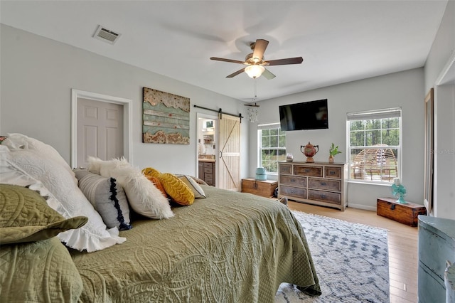 21320 Paradise Way, Eustis, FL 32736 - bedroom featuring multiple windows, wood finished floors, a barn door, and a ceiling fan