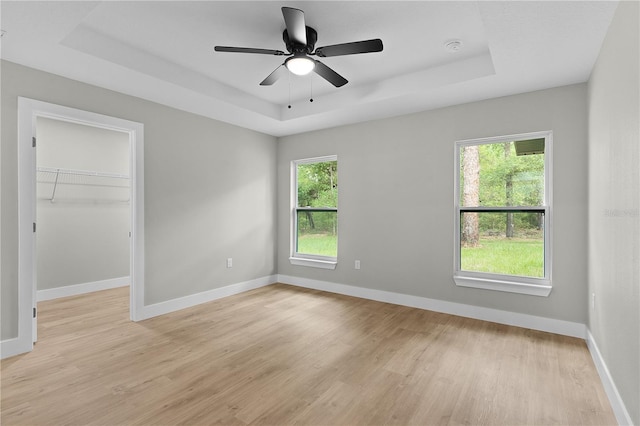 1115 W Geneva Pl, Citrus Springs, FL 34434 - unfurnished bedroom featuring a raised ceiling, light wood-style flooring, multiple windows, and a spacious closet