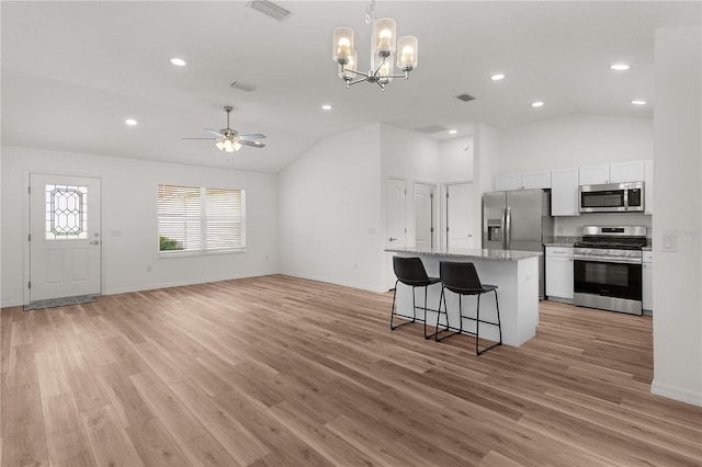 1313 Arredondo Dr, The Villages, FL 32162 - kitchen featuring stainless steel appliances, lofted ceiling, a center island, a breakfast bar, and white cabinets