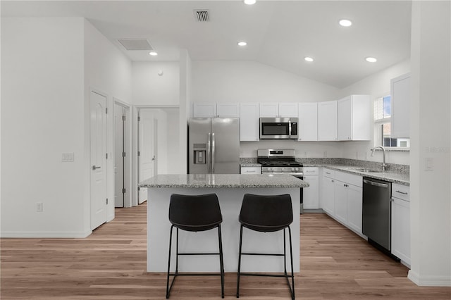 1313 Arredondo Dr, The Villages, FL 32162 - kitchen featuring appliances with stainless steel finishes, a center island, a sink, vaulted ceiling, and a kitchen breakfast bar