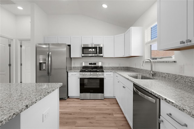 1313 Arredondo Dr, The Villages, FL 32162 - kitchen featuring appliances with stainless steel finishes, a sink, lofted ceiling, light wood-style flooring, and white cabinets