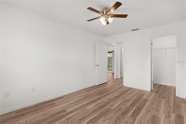 1313 Arredondo Dr, The Villages, FL 32162 - unfurnished bedroom featuring light wood finished floors, baseboards, a walk in closet, and ceiling fan