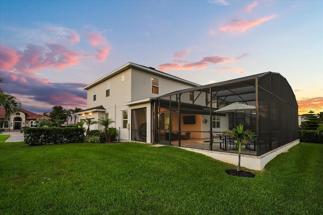 17700 Sawgrass Run, Tavares, FL 32778 - back of property featuring a yard, a patio area, stucco siding, and glass enclosure