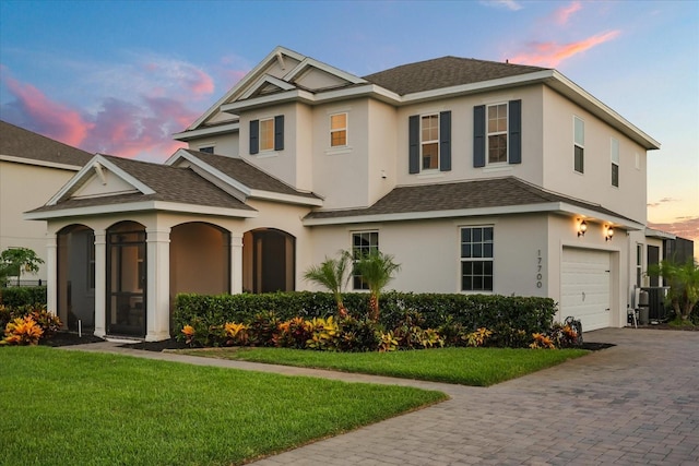 17700 Sawgrass Run, Tavares, FL 32778 - traditional home with roof with shingles, stucco siding, decorative driveway, and an attached garage
