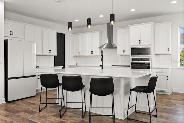 17700 Sawgrass Run, Tavares, FL 32778 - kitchen with stainless steel appliances, wall chimney exhaust hood, a kitchen island with sink, recessed lighting, and white cabinetry