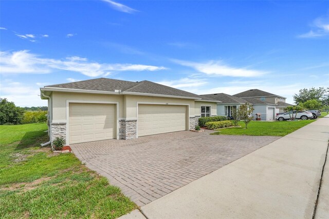 641 Black Eagle Dr, Groveland, FL 34736 - view of front of property featuring an attached garage, decorative driveway, stone siding, a front yard, and stucco siding