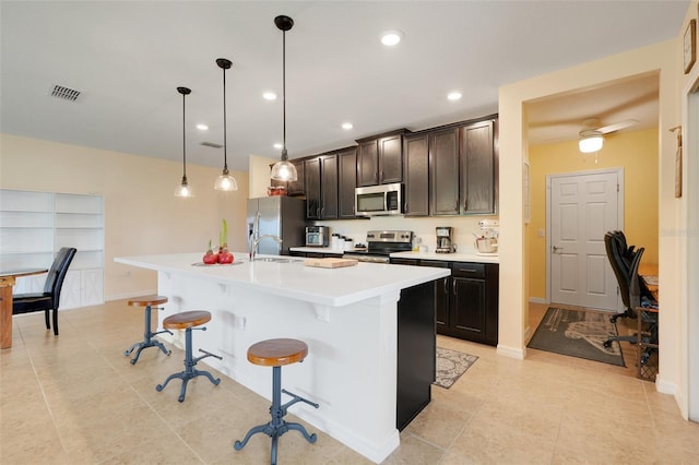 641 Black Eagle Dr, Groveland, FL 34736 - kitchen with appliances with stainless steel finishes, a breakfast bar area, an island with sink, light countertops, and light tile patterned floors
